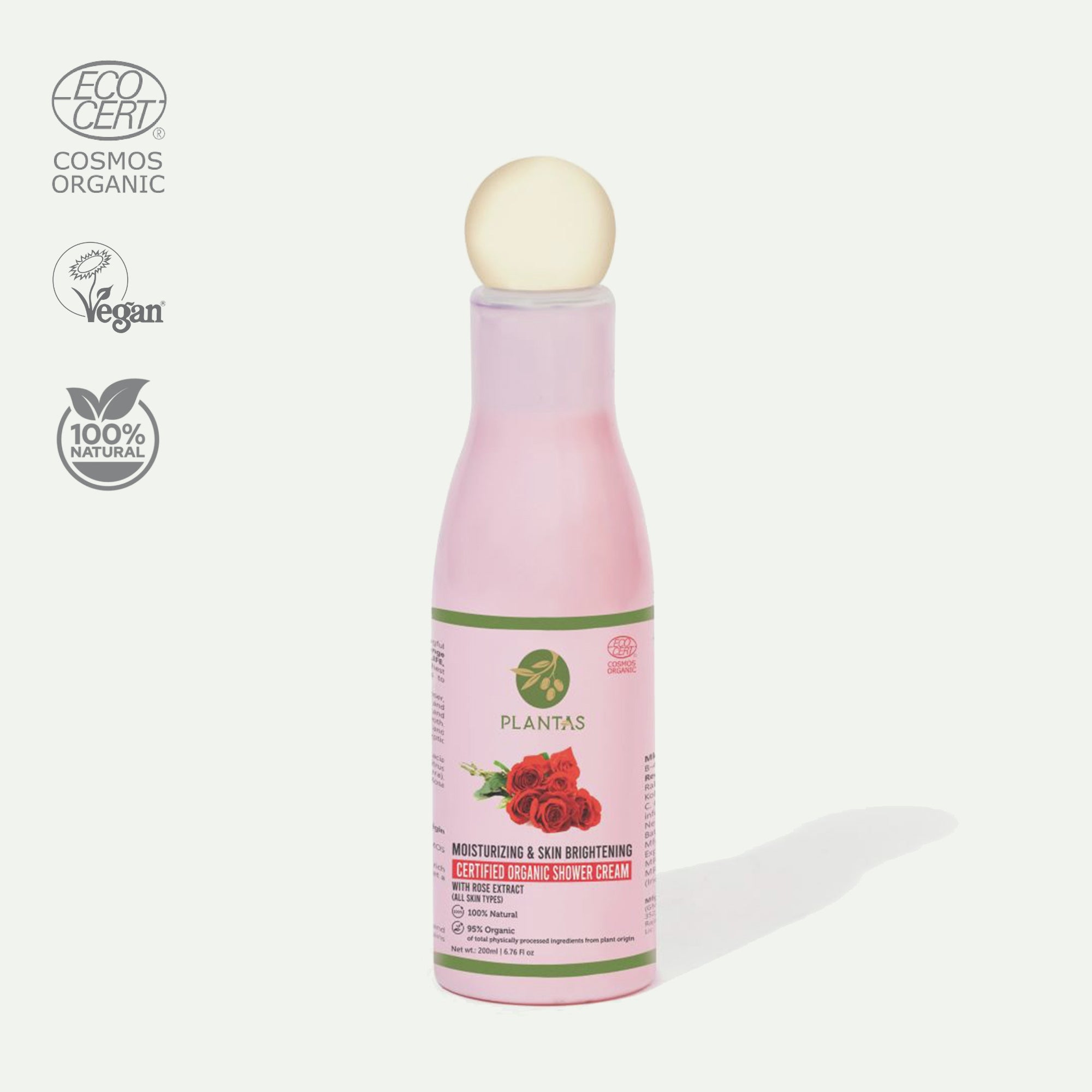 A bottle of Plantas Organic Moisturizing & Skin Brightening Shower Cream with a pink label, a white pump, and logos indicating it is organic and vegan.