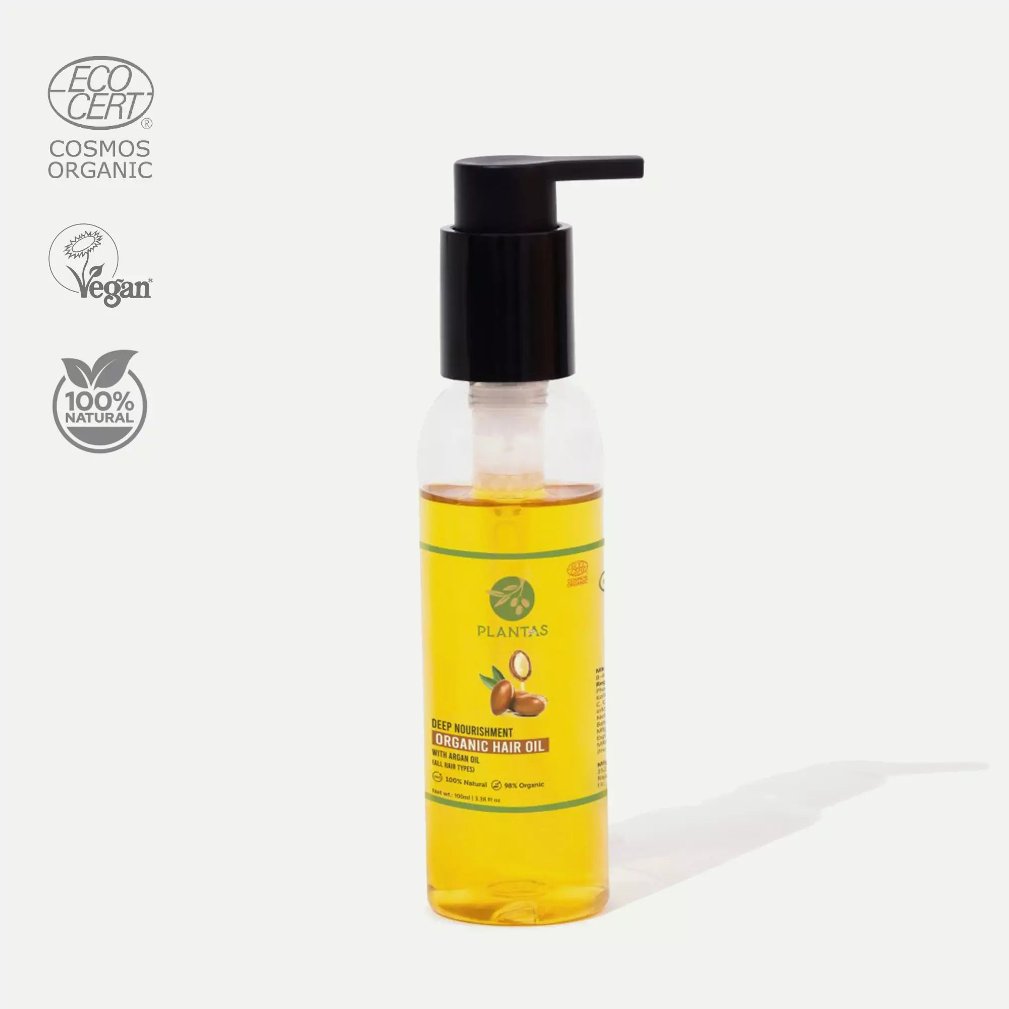 A bottle of Plantas Organic Hair Oil with a pump dispenser, enriched with natural oils. The label displays organic certification and indicates the product is vegan.